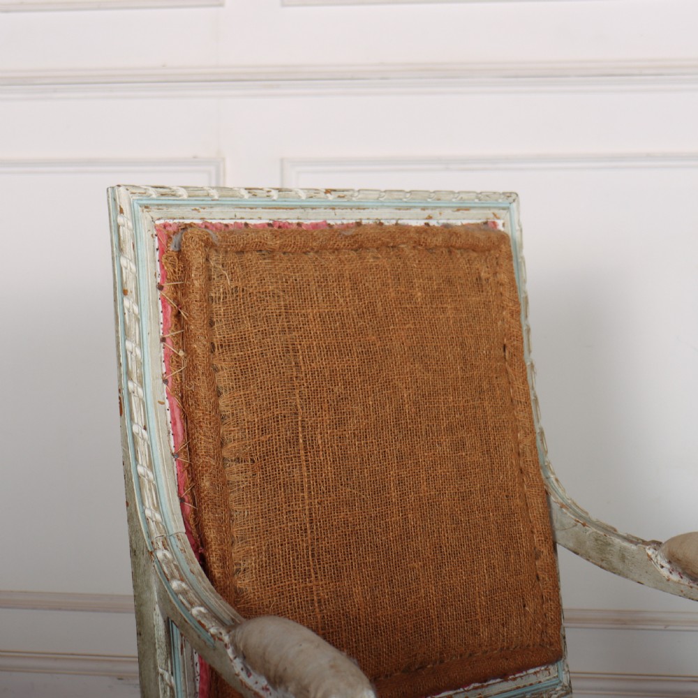 A pair of antique French Louis XVI open armchairs featuring carved, distressed light blue painted frames, fluted legs, and exposed hessian upholstery. View III