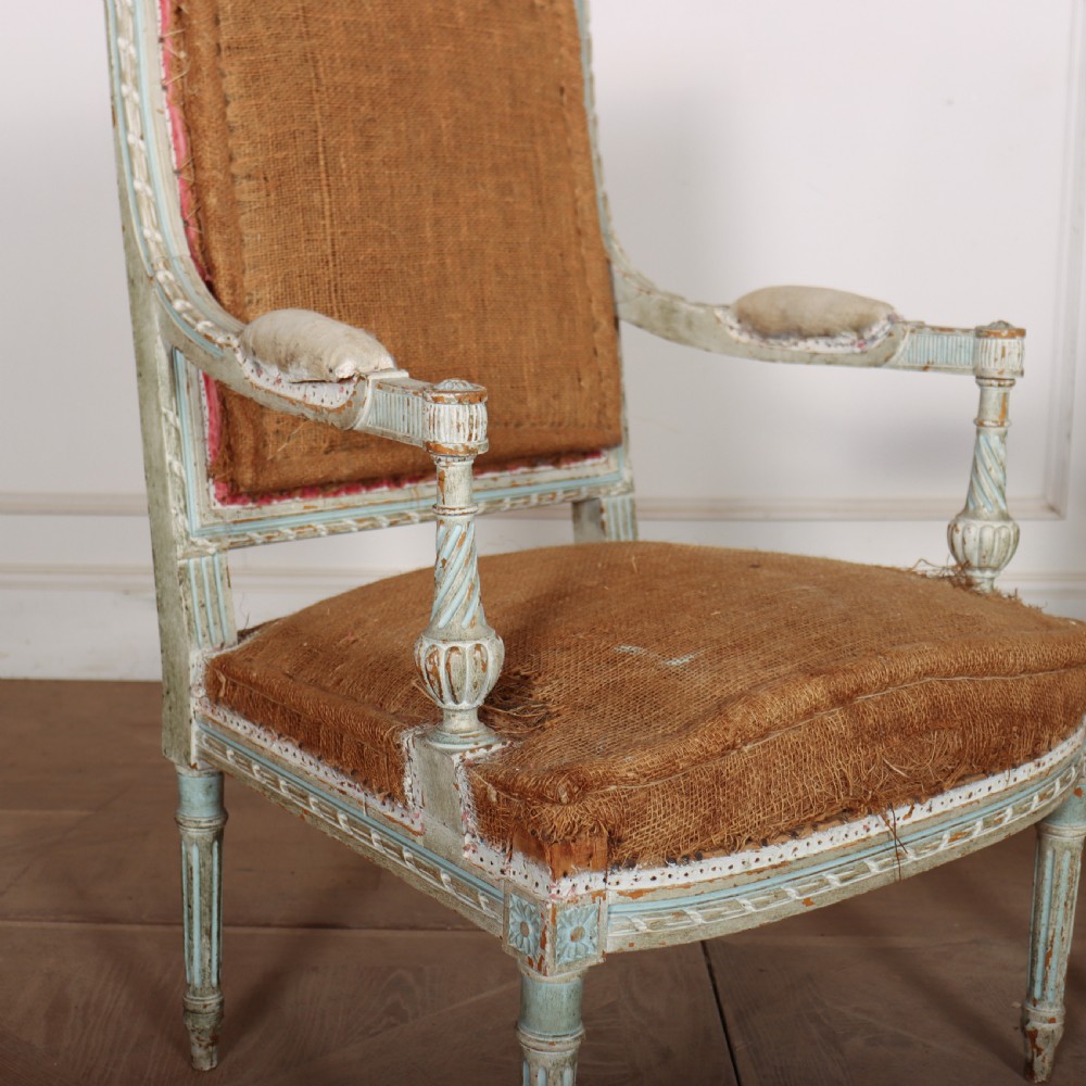 A pair of antique French Louis XVI open armchairs featuring carved, distressed light blue painted frames, fluted legs, and exposed hessian upholstery. View IV