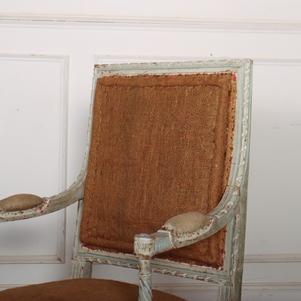 A pair of antique French Louis XVI open armchairs featuring carved, distressed light blue painted frames, fluted legs, and exposed hessian upholstery. View VII