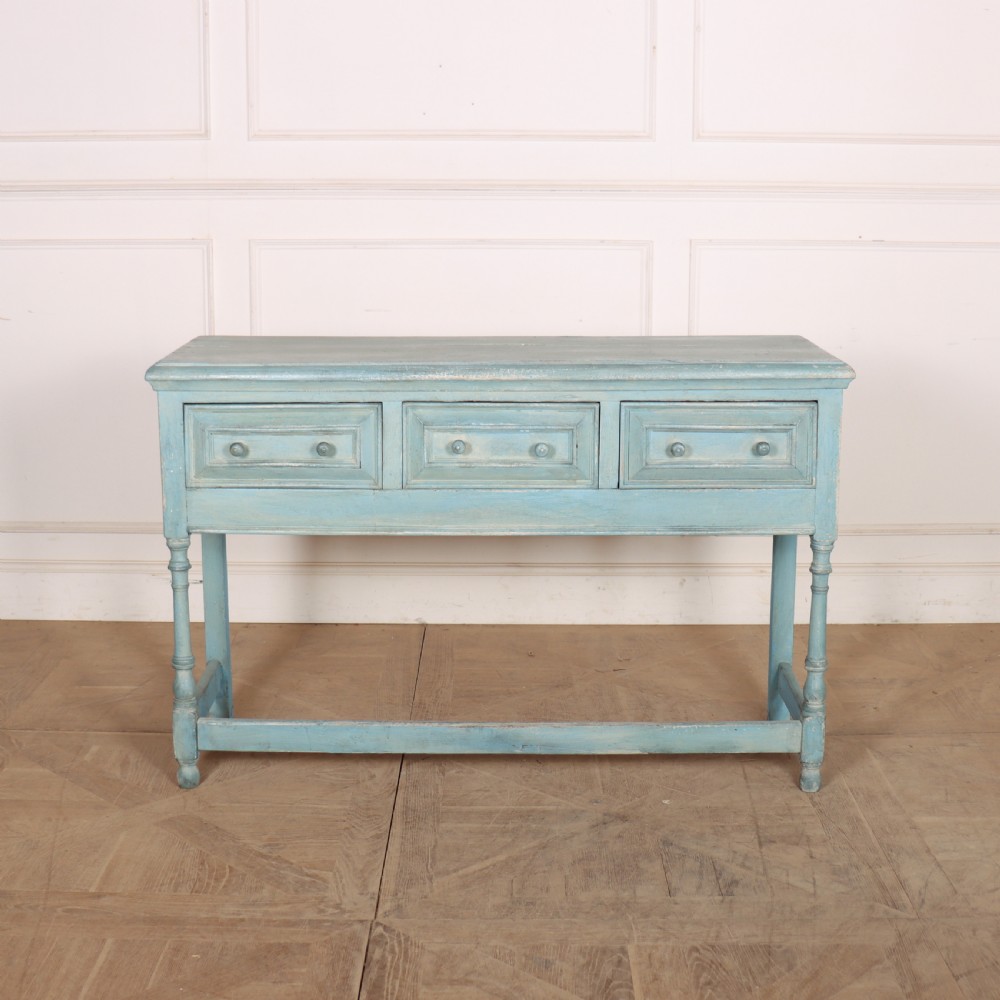 A pale blue painted wooden dresser base featuring three inline drawers with small wooden knobs and turned front legs connected by a low stretcher.