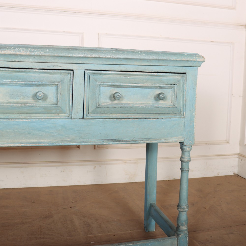 A pale blue painted wooden dresser base featuring three inline drawers with small wooden knobs and turned front legs connected by a low stretcher. View II