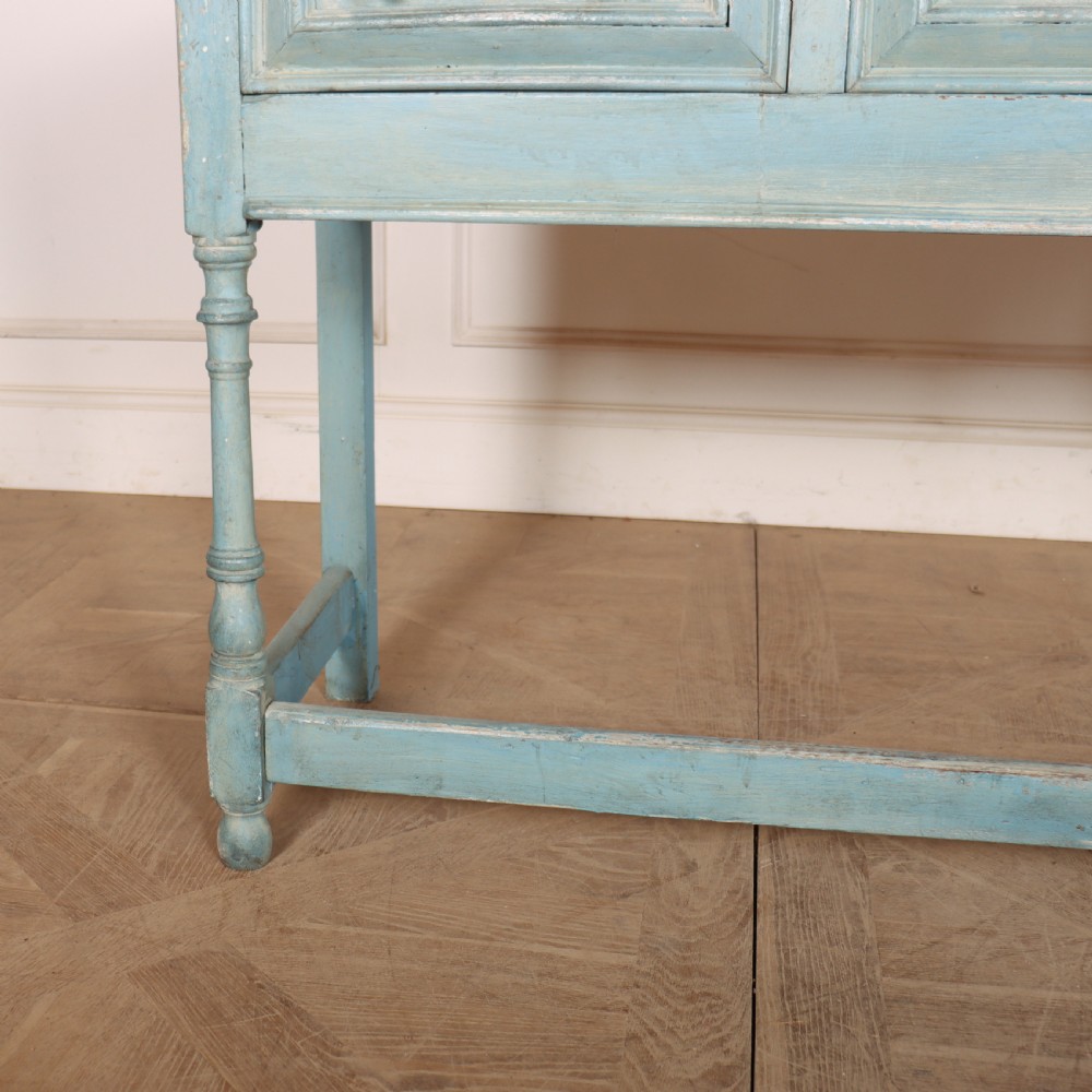 A pale blue painted wooden dresser base featuring three inline drawers with small wooden knobs and turned front legs connected by a low stretcher. View IV