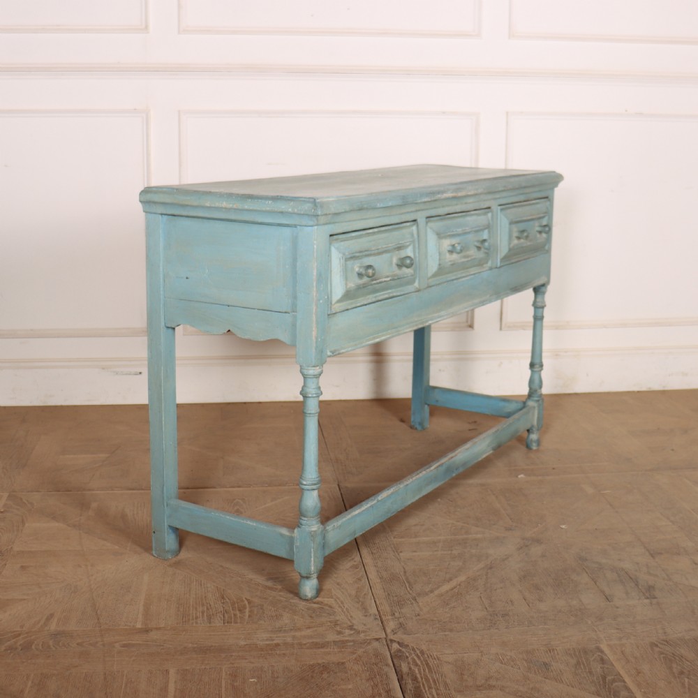 A pale blue painted wooden dresser base featuring three inline drawers with small wooden knobs and turned front legs connected by a low stretcher. View VII
