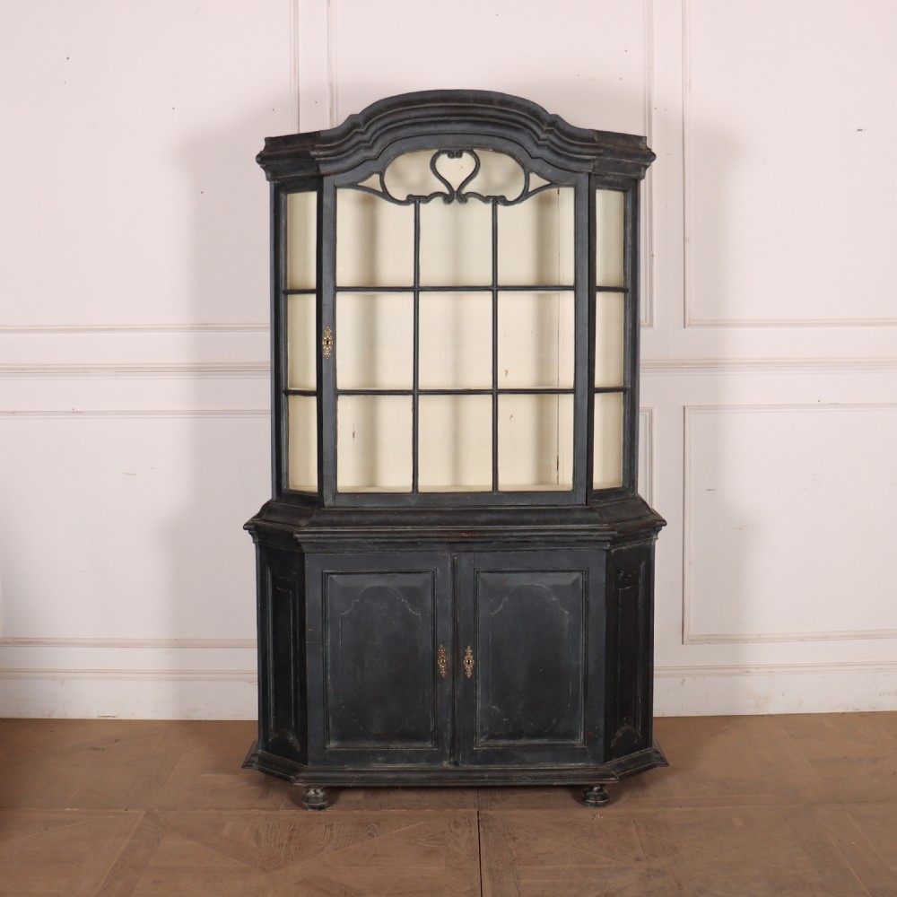 A tall, dark charcoal grey painted Dutch vitrine cabinet featuring a shaped bonnet top, glazed upper doors with curved astragal glazing bars, a cream interior, and panelled double lower doors.