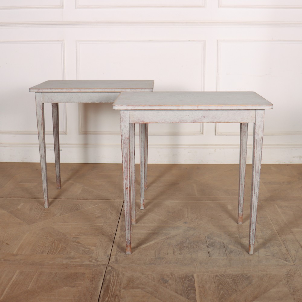 A pair of tall rectangular Swedish side tables with distressed pale grey painted finishes and slender tapered legs.