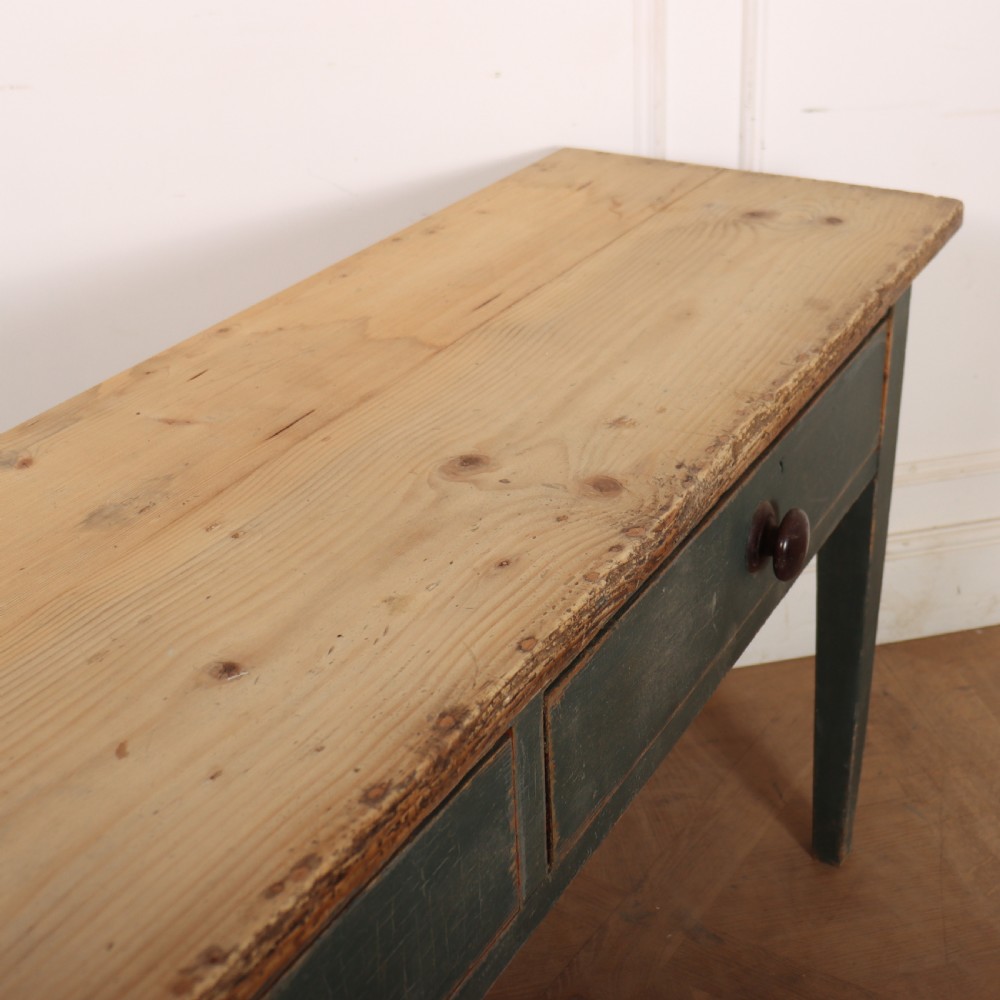 An antique Scottish console table featuring a muted green painted base with two drawers, dark wooden turned knobs, square tapered legs, and a natural pine top. View X