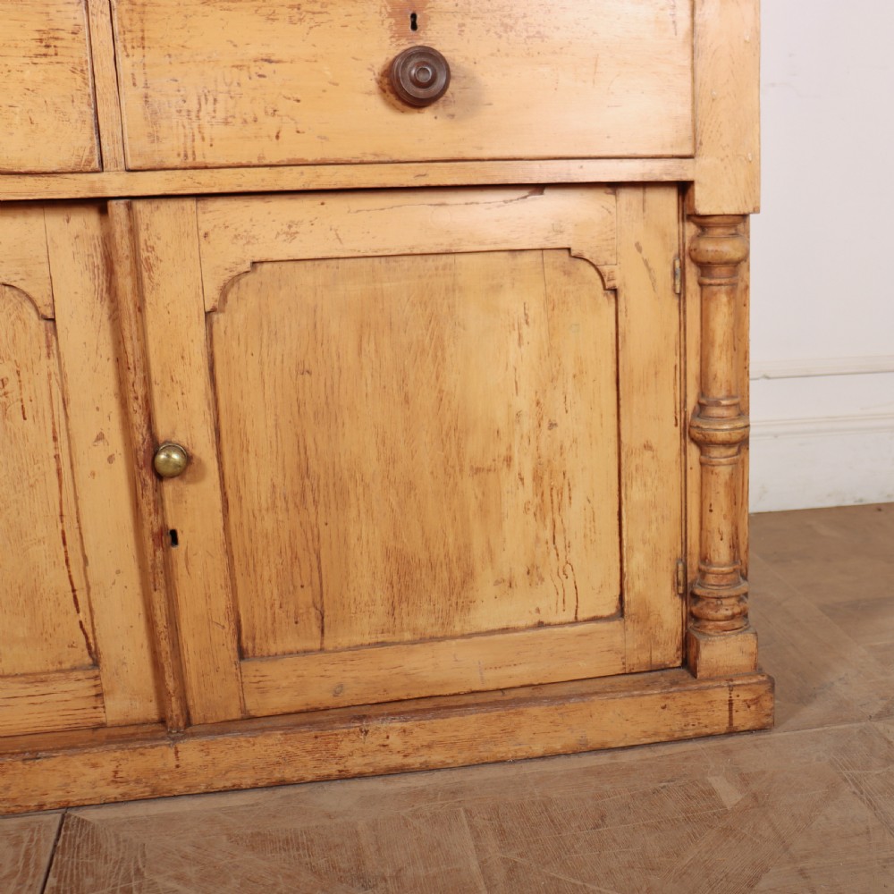 An antique pine glazed dresser with two upper glazed doors revealing a vibrant blue interior above two drawers and two cabinet doors. View III