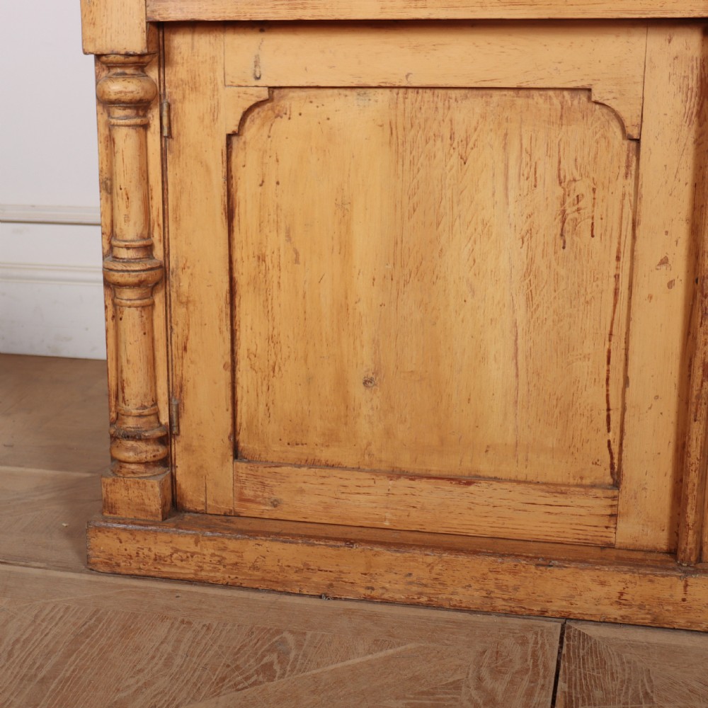An antique pine glazed dresser with two upper glazed doors revealing a vibrant blue interior above two drawers and two cabinet doors. View IV