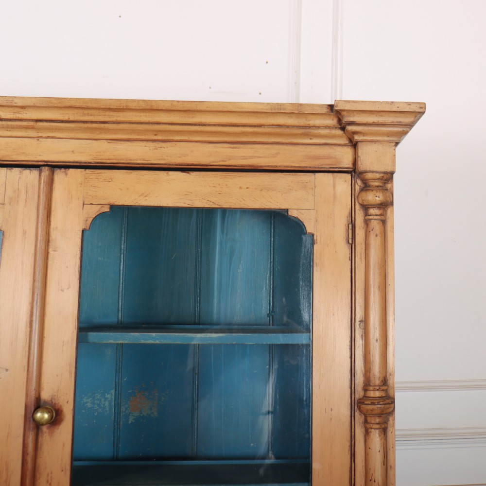 An antique pine glazed dresser with two upper glazed doors revealing a vibrant blue interior above two drawers and two cabinet doors. View VI