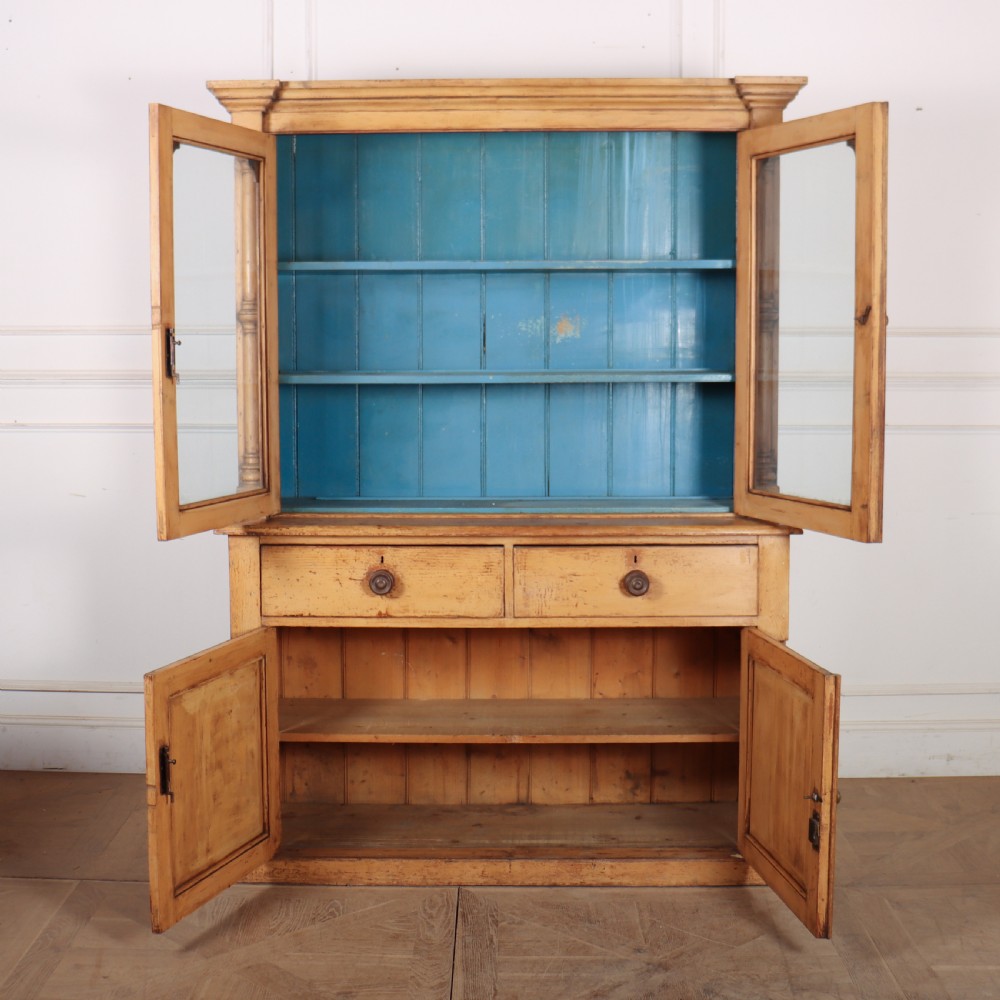 An antique pine glazed dresser with two upper glazed doors revealing a vibrant blue interior above two drawers and two cabinet doors. View VII