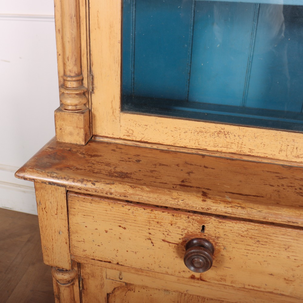 An antique pine glazed dresser with two upper glazed doors revealing a vibrant blue interior above two drawers and two cabinet doors. View IX