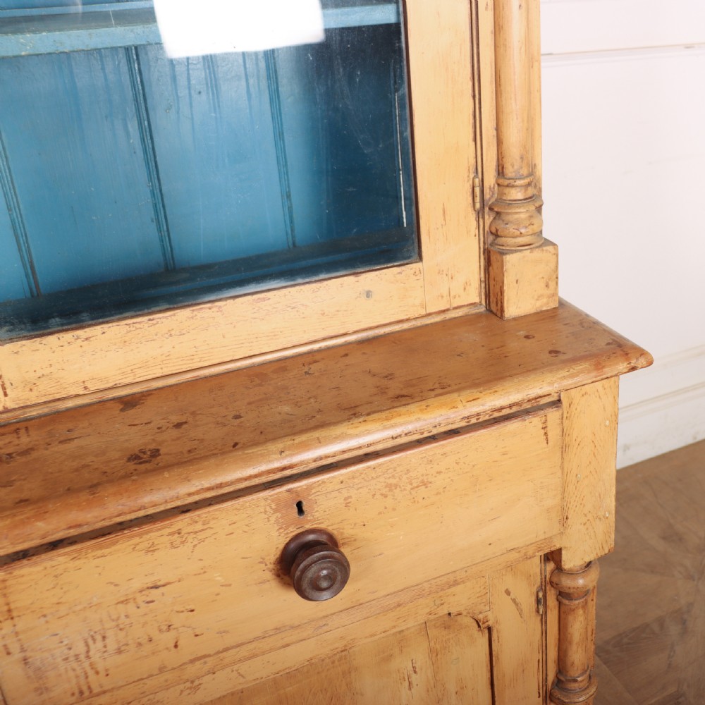 An antique pine glazed dresser with two upper glazed doors revealing a vibrant blue interior above two drawers and two cabinet doors. View X