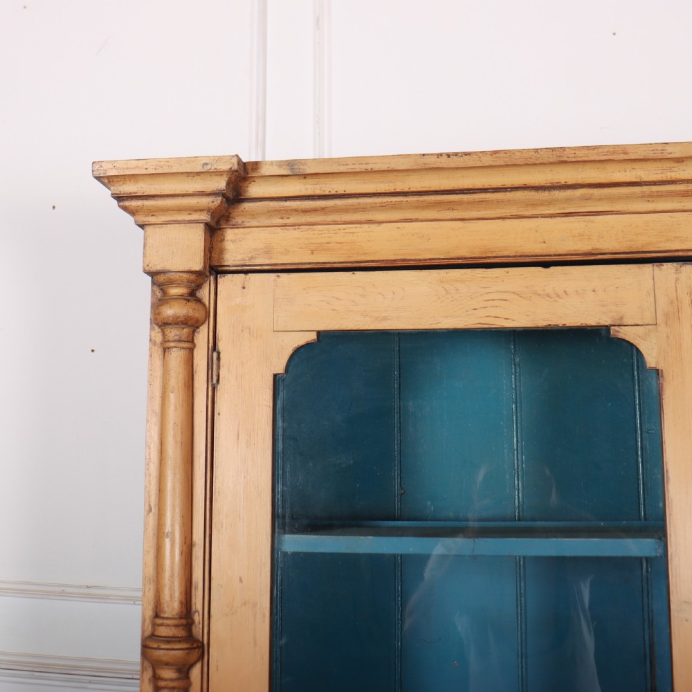 A two-tier antique pine glazed dresser with a blue painted interior, turned corner columns, two drawers, and two lower wooden cabinet doors. View II