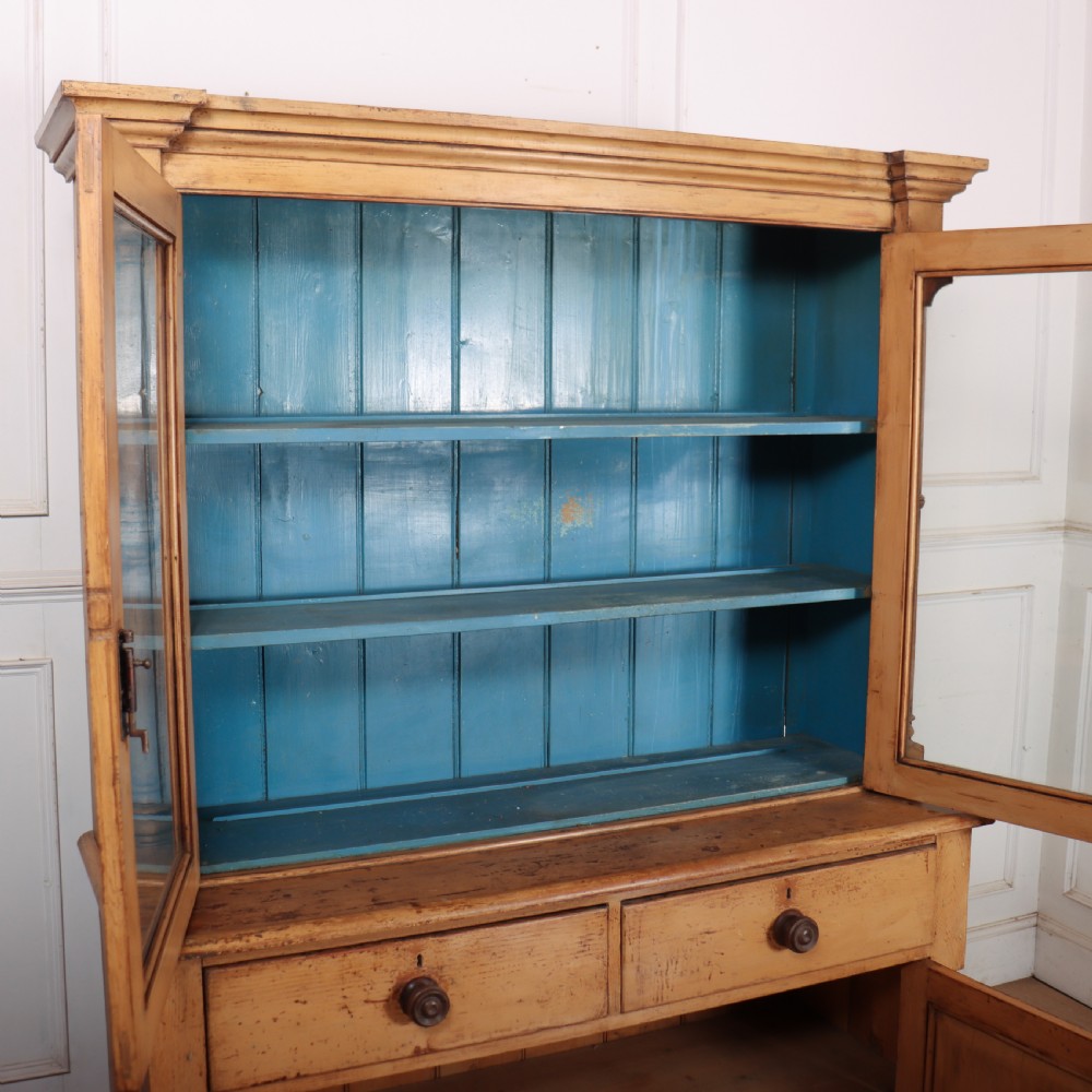 A two-tier antique pine glazed dresser with a blue painted interior, turned corner columns, two drawers, and two lower wooden cabinet doors. View IX