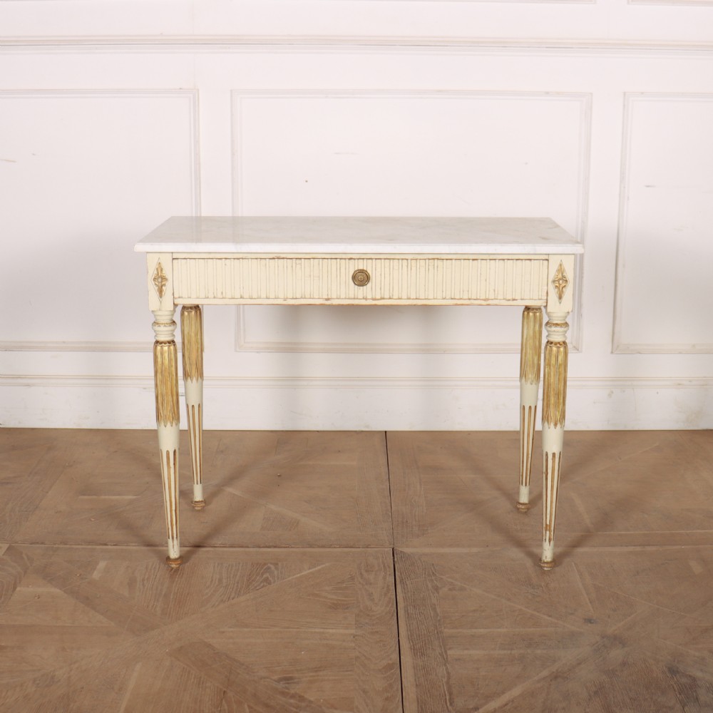 An off-white painted Swedish side table featuring a white marble top, fluted frieze with a central drawer knob, and tapered fluted legs with gilded accents. View II