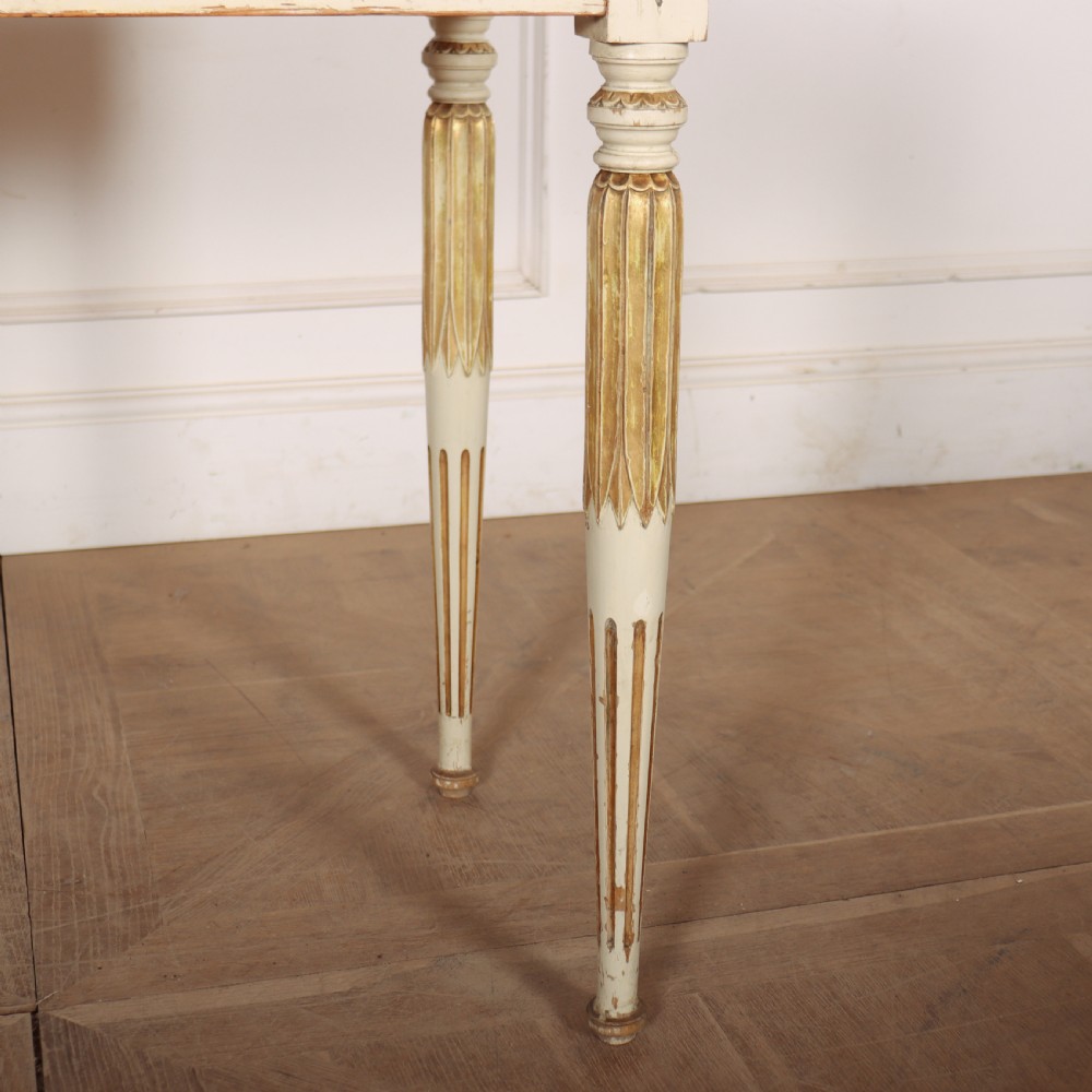An off-white painted Swedish side table featuring a white marble top, fluted frieze with a central drawer knob, and tapered fluted legs with gilded accents. View VI