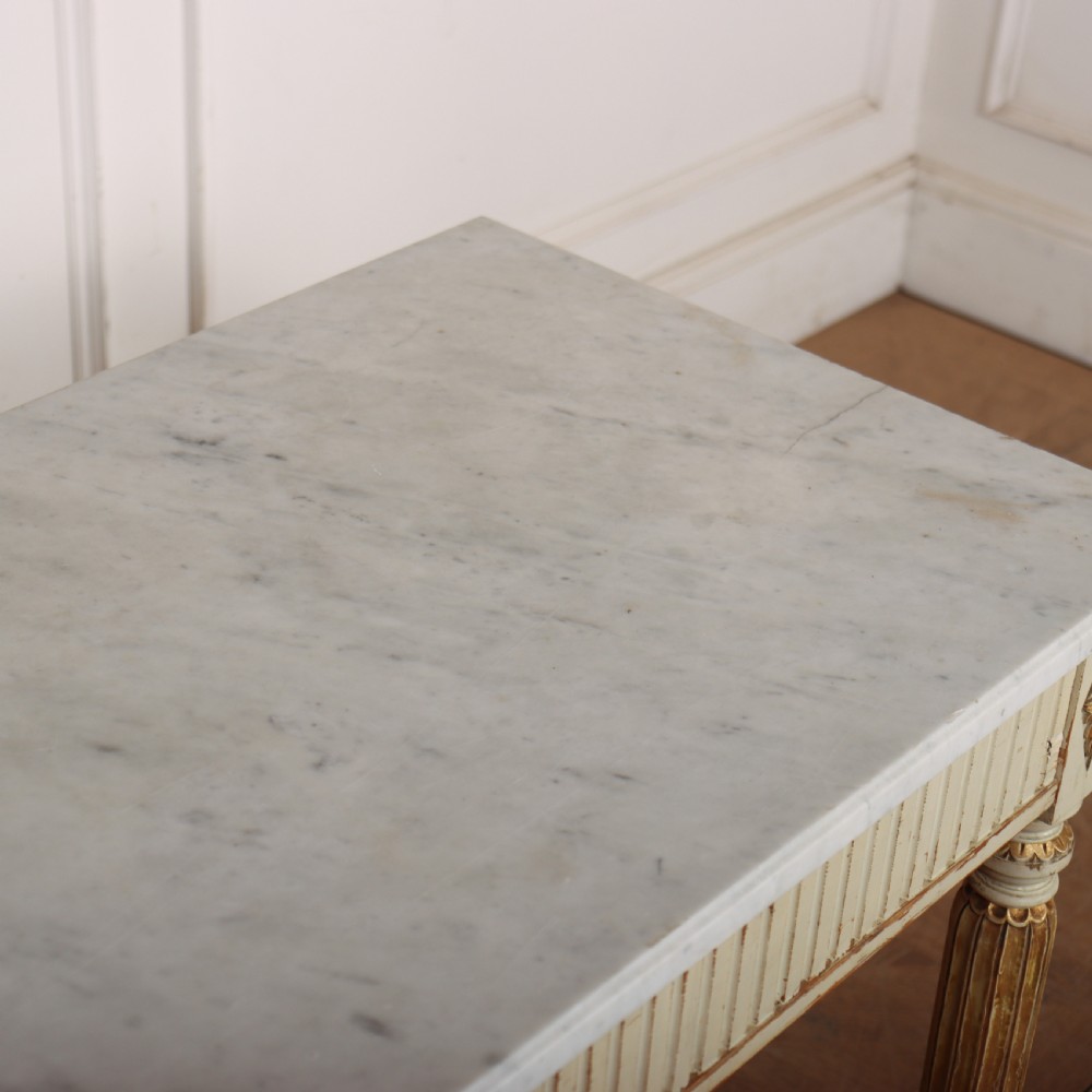 An off-white painted Swedish side table featuring a white marble top, fluted frieze with a central drawer knob, and tapered fluted legs with gilded accents. View IX