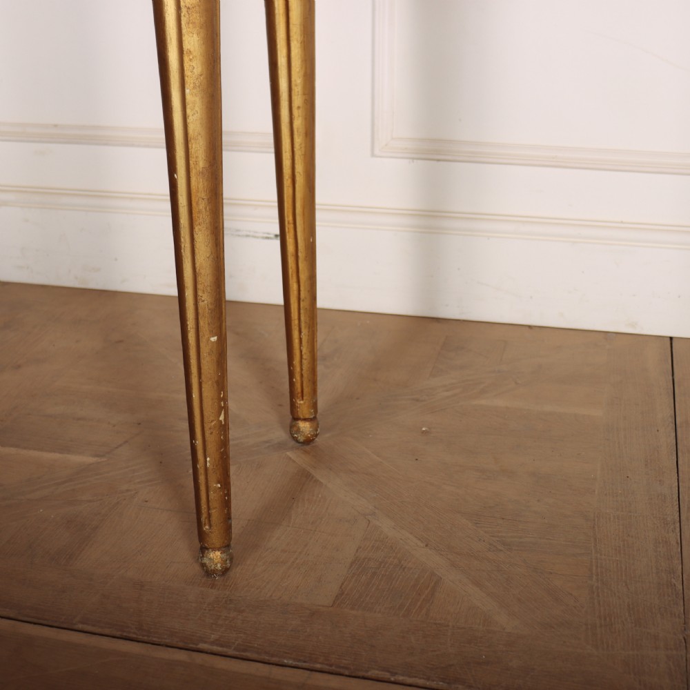 A rectangular gilded console table featuring a grey marble top, carved rams head central motif, rosettes, and tapered legs. View V