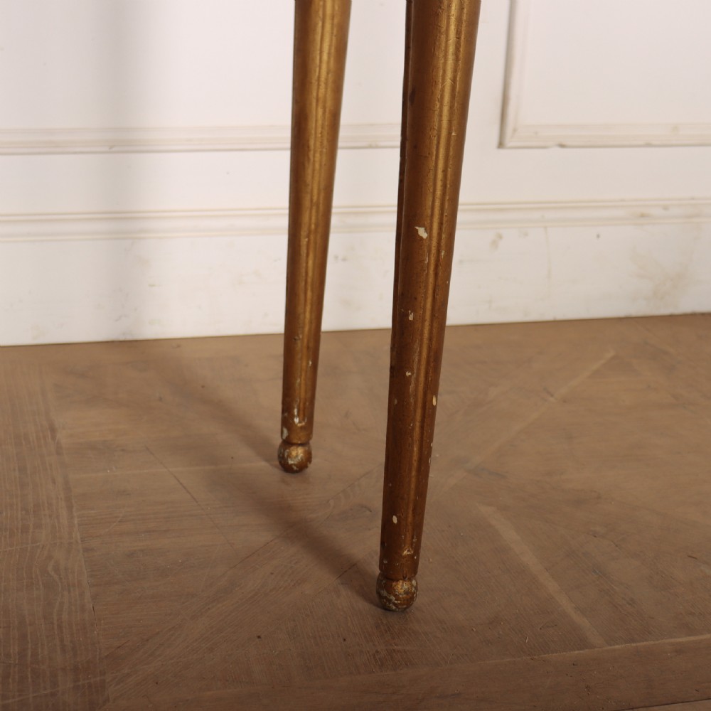 A rectangular gilded console table featuring a grey marble top, carved rams head central motif, rosettes, and tapered legs. View VII