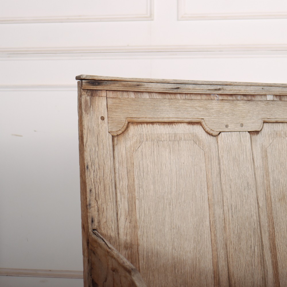An antique bleached oak settle featuring a high panelled backrest, shaped armrests, turned legs, and a webbed seat base. View II