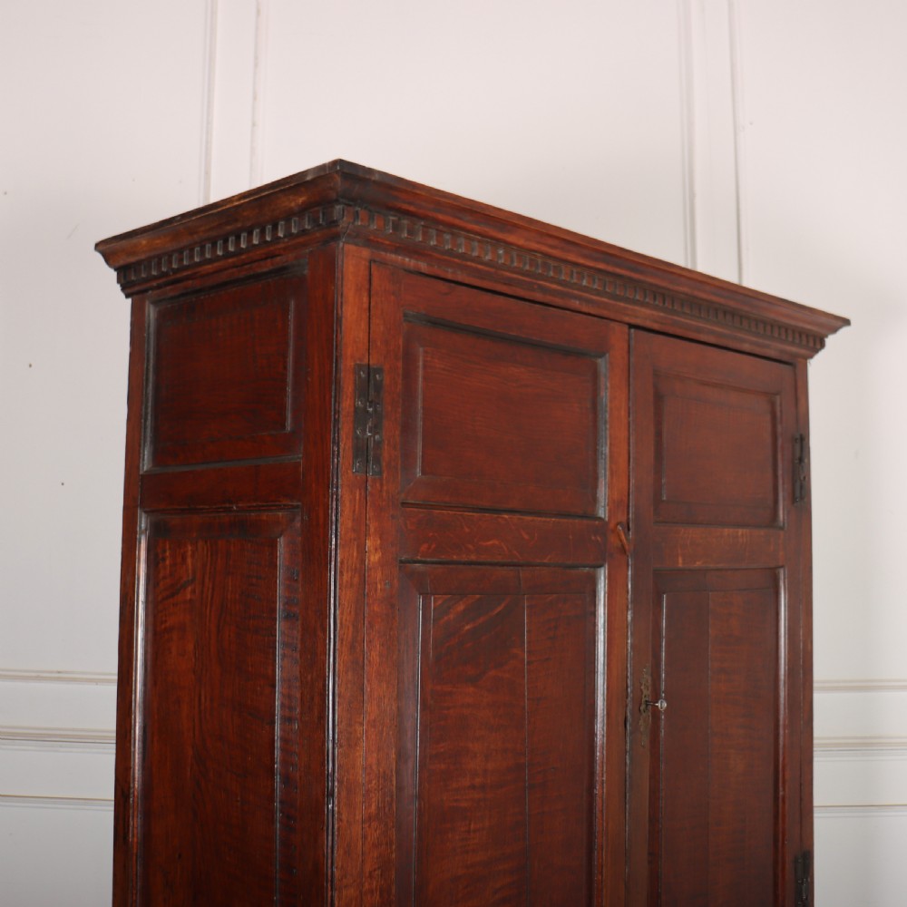 An antique two-part English oak linen press featuring upper fielded panel cupboard doors and a base with six drawers fitted with brass drop handles. View II