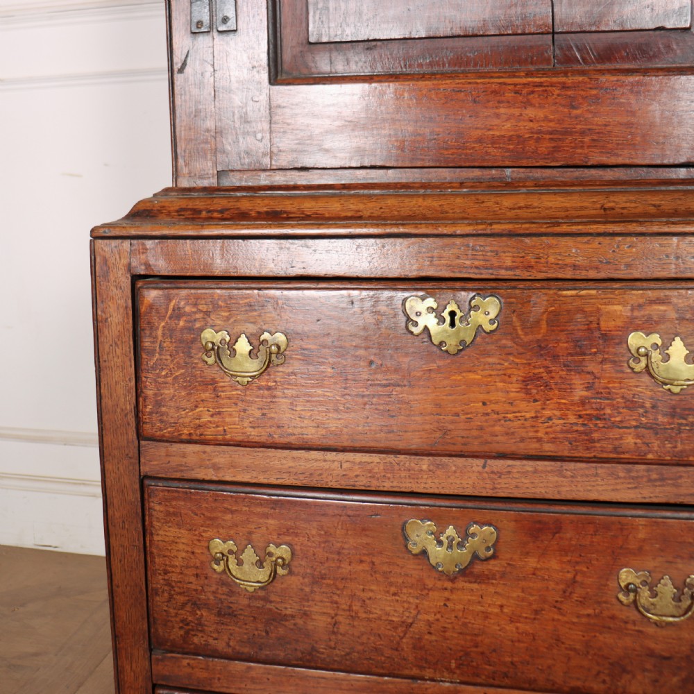 An antique two-part English oak linen press featuring upper fielded panel cupboard doors and a base with six drawers fitted with brass drop handles. View V