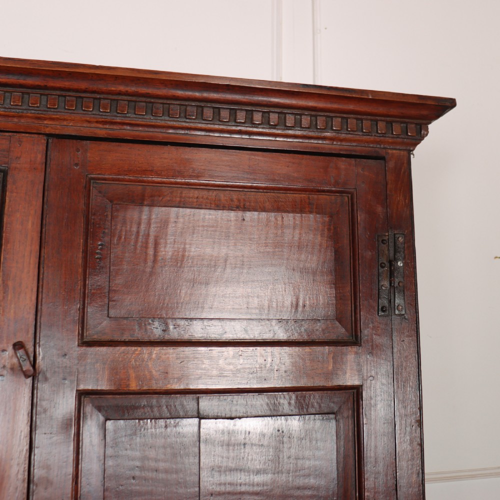 An antique two-part English oak linen press featuring upper fielded panel cupboard doors and a base with six drawers fitted with brass drop handles. View X