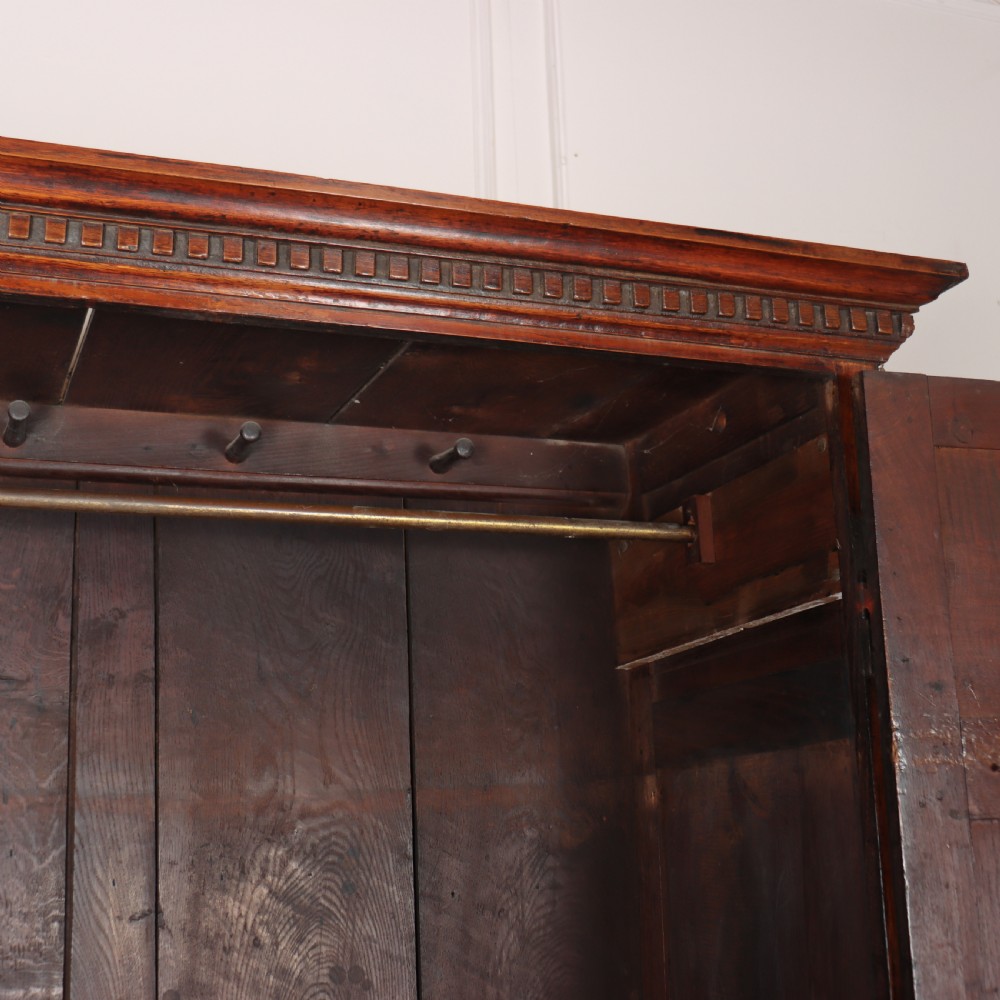 An antique two-part English oak linen press featuring upper fielded panel cupboard doors and a base with six drawers fitted with brass drop handles. View XII