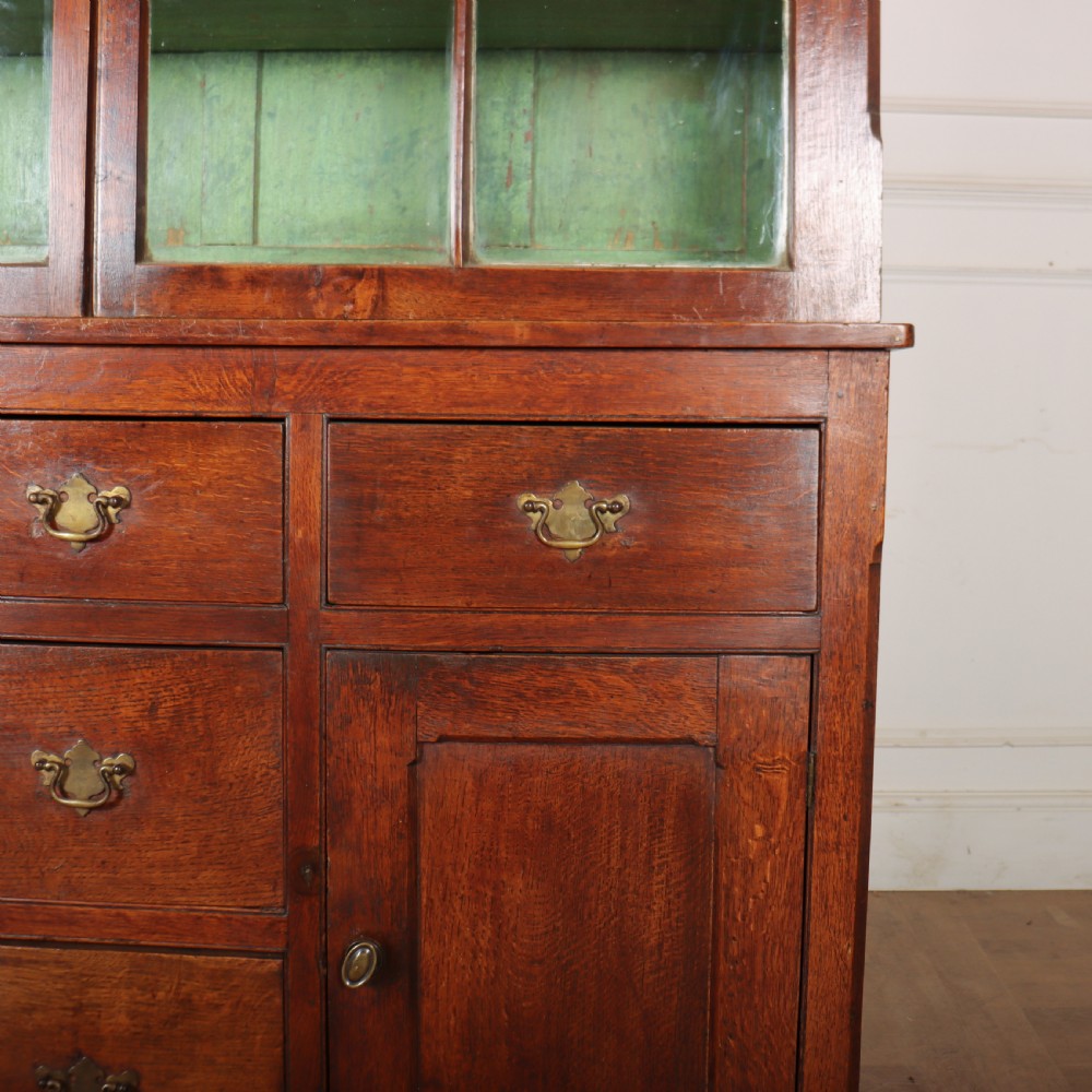A large two-part oak kitchen dresser with a glazed upper section featuring a green painted interior above a base with five drawers and two panelled cupboard doors. View II