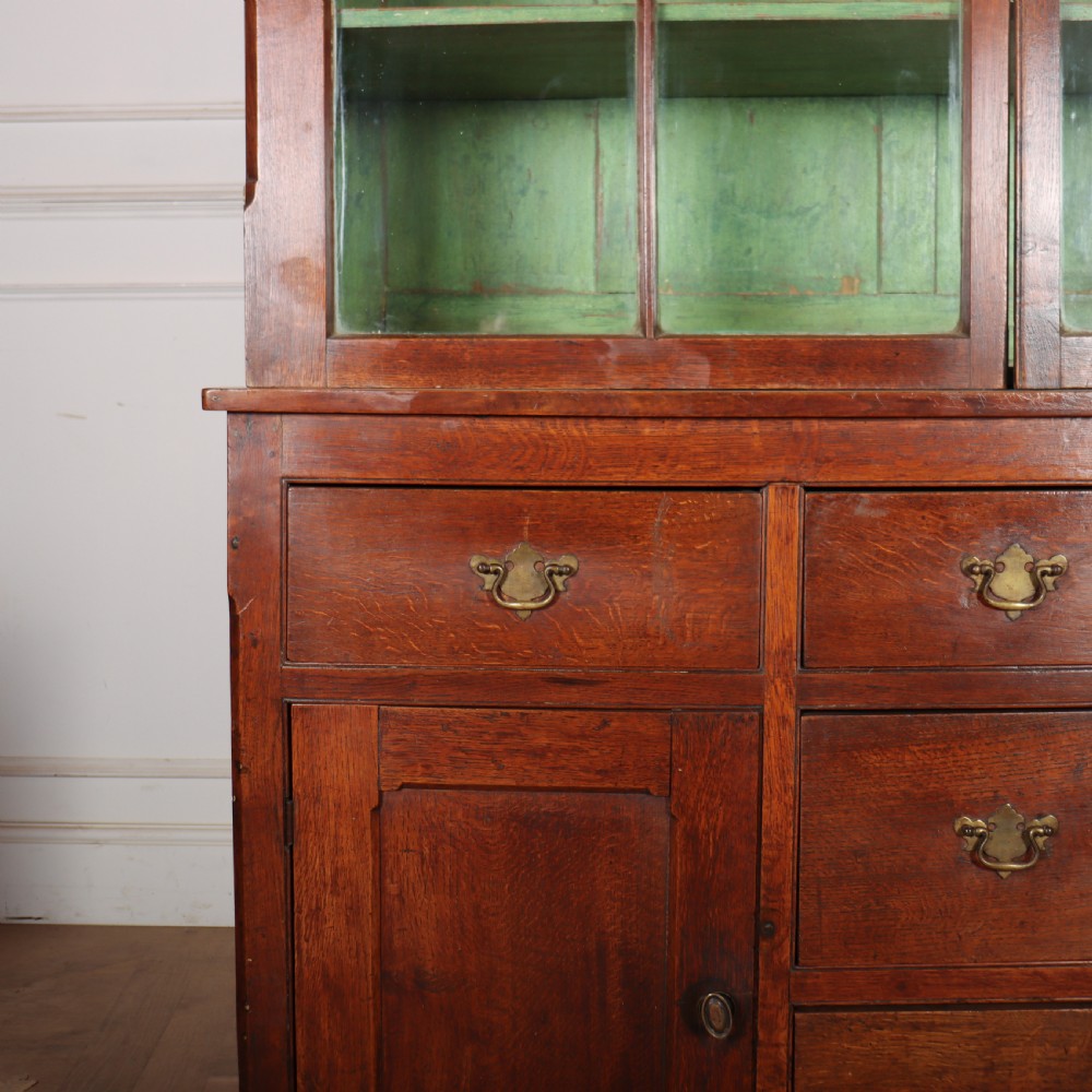 A large two-part oak kitchen dresser with a glazed upper section featuring a green painted interior above a base with five drawers and two panelled cupboard doors. View III