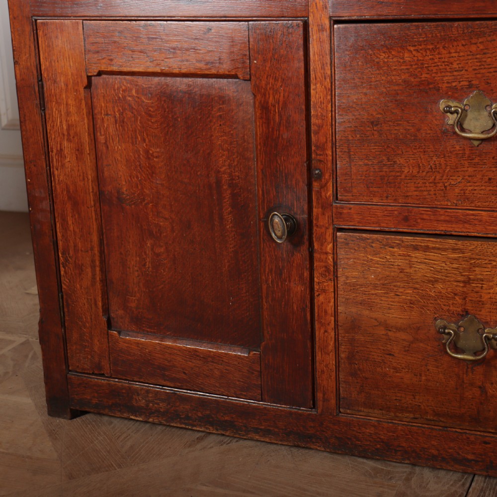 A large two-part oak kitchen dresser with a glazed upper section featuring a green painted interior above a base with five drawers and two panelled cupboard doors. View V