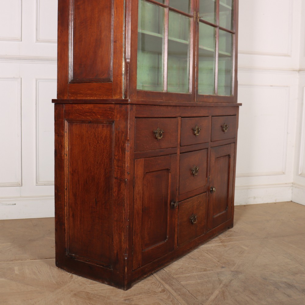 A large two-part oak kitchen dresser with a glazed upper section featuring a green painted interior above a base with five drawers and two panelled cupboard doors. View IX