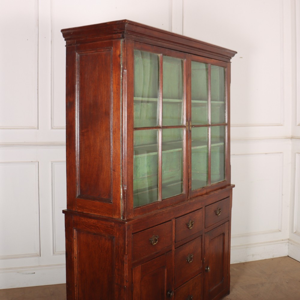 A large two-part oak kitchen dresser with a glazed upper section featuring a green painted interior above a base with five drawers and two panelled cupboard doors. View X