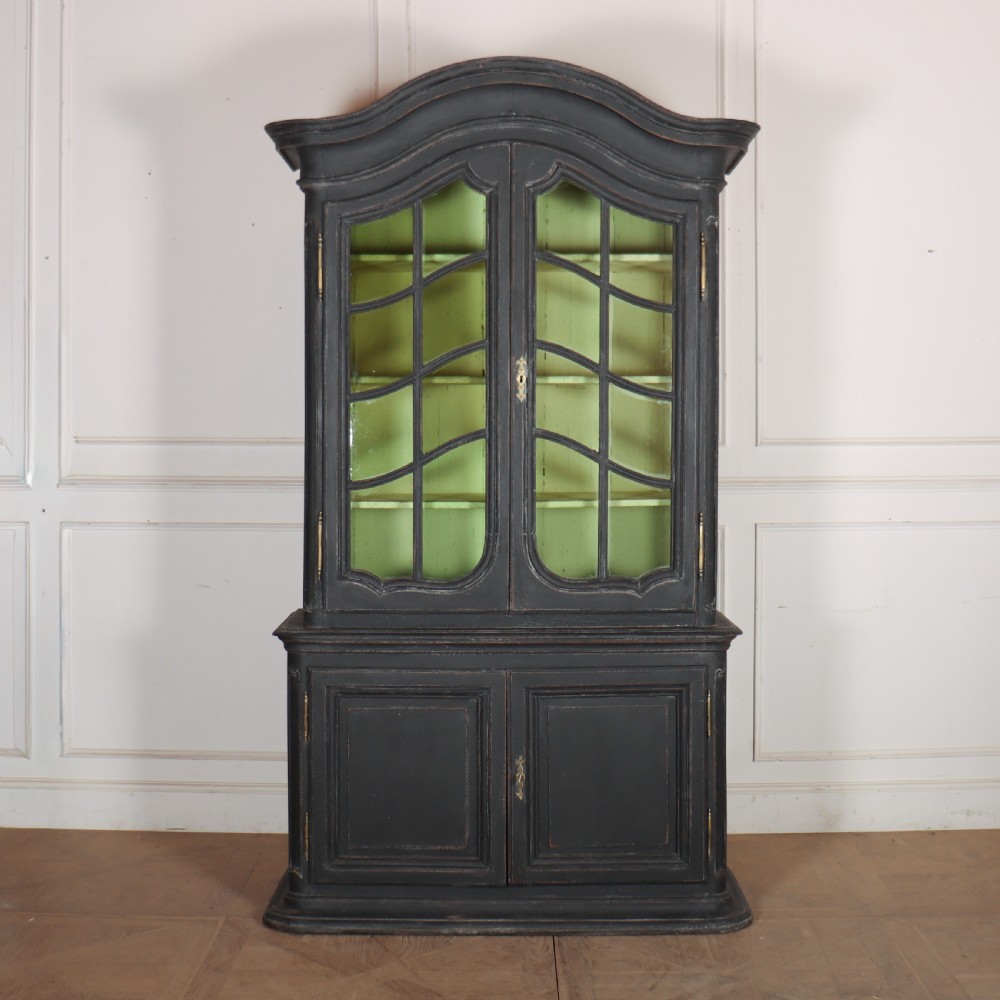 A two-piece black painted Dutch cabinet featuring arched glazed upper doors with wavy astragal bars, a green interior, and solid double doors below.