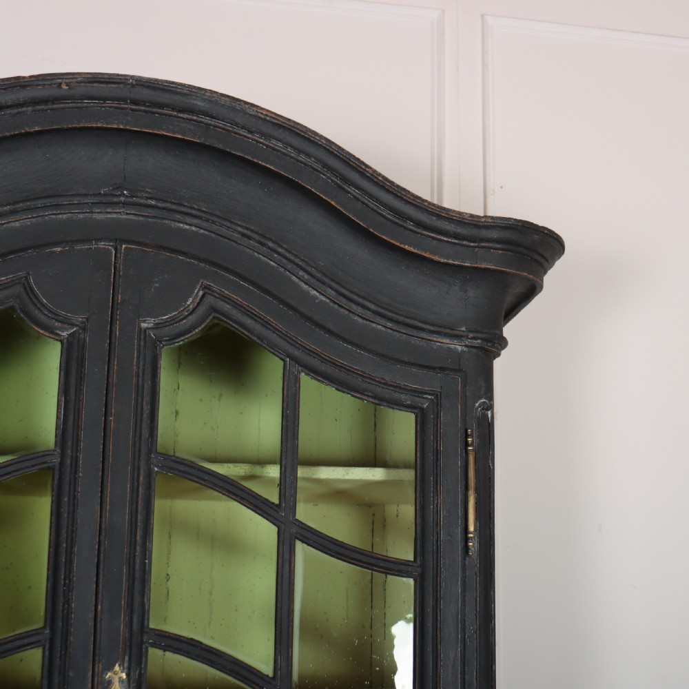 A two-piece black painted Dutch cabinet featuring arched glazed upper doors with wavy astragal bars, a green interior, and solid double doors below. View III