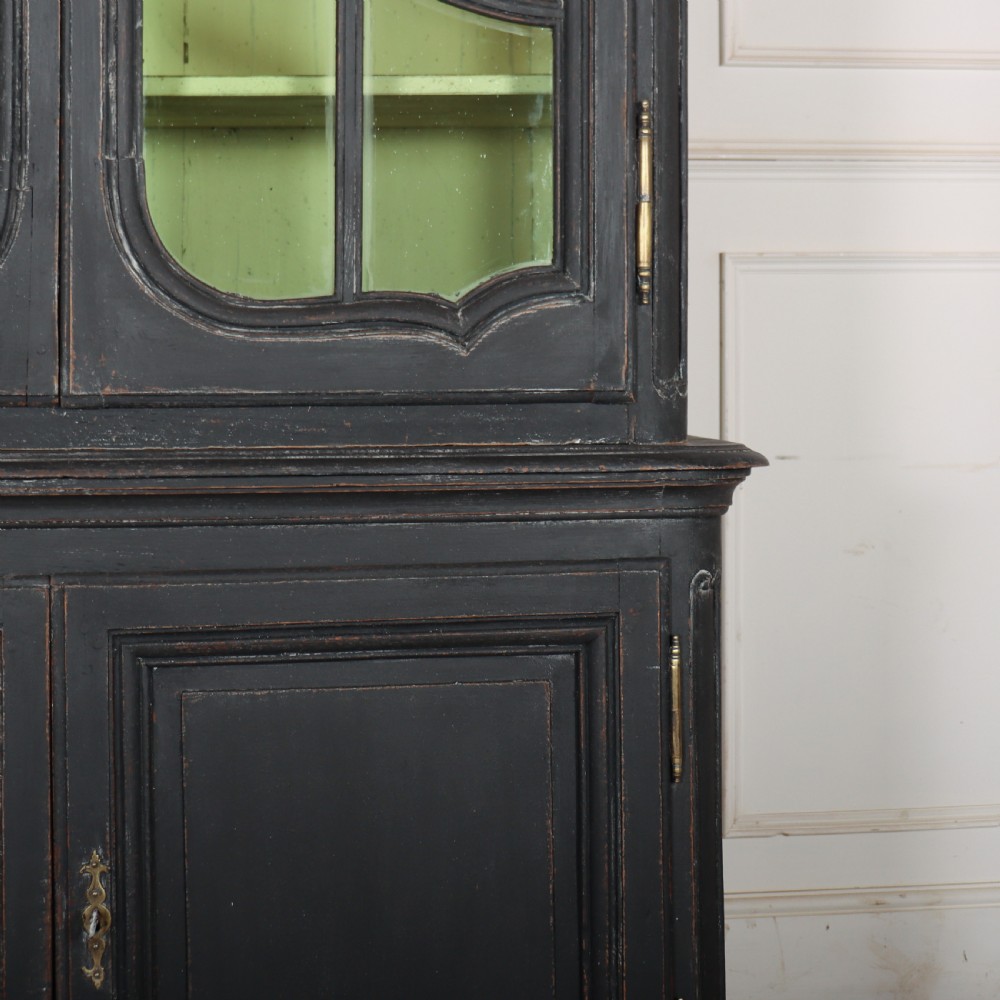 A two-piece black painted Dutch cabinet featuring arched glazed upper doors with wavy astragal bars, a green interior, and solid double doors below. View V