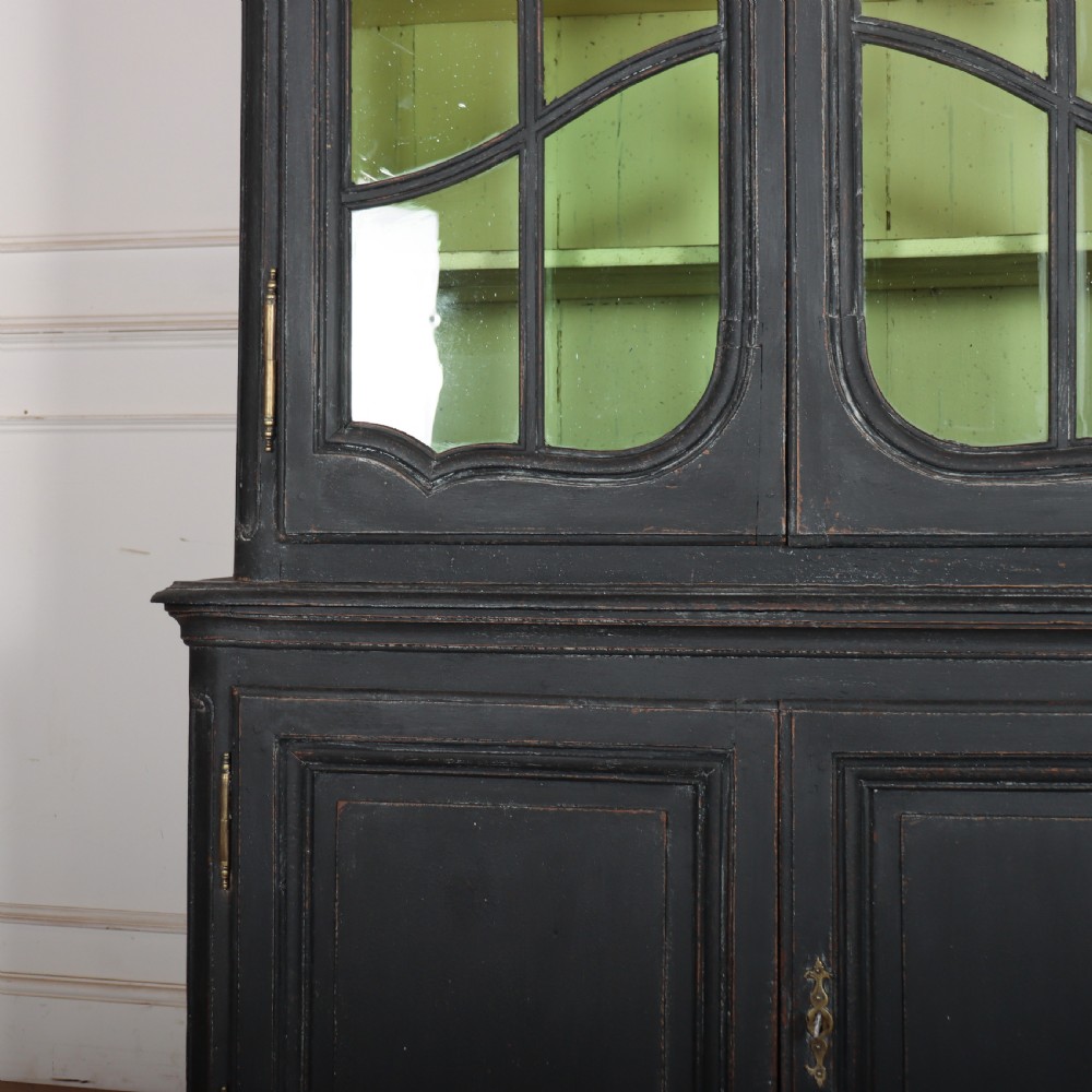 A two-piece black painted Dutch cabinet featuring arched glazed upper doors with wavy astragal bars, a green interior, and solid double doors below. View VI