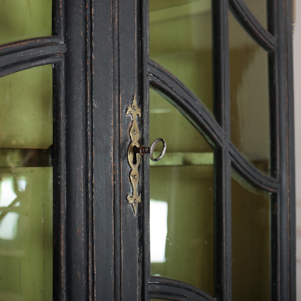 A two-piece black painted Dutch cabinet featuring arched glazed upper doors with wavy astragal bars, a green interior, and solid double doors below. View IX