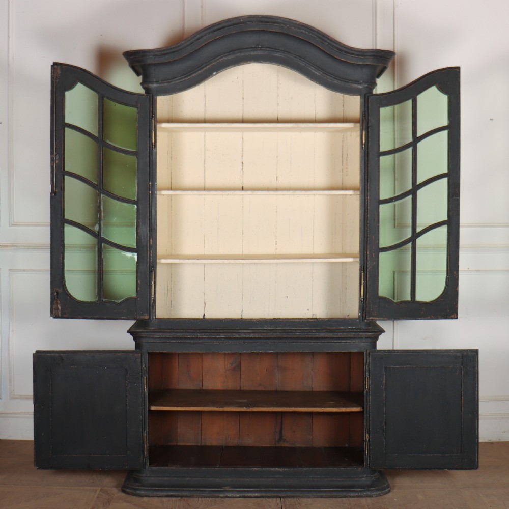 A two-piece black painted Dutch cabinet featuring arched glazed upper doors with wavy astragal bars, a green interior, and solid double doors below. View X