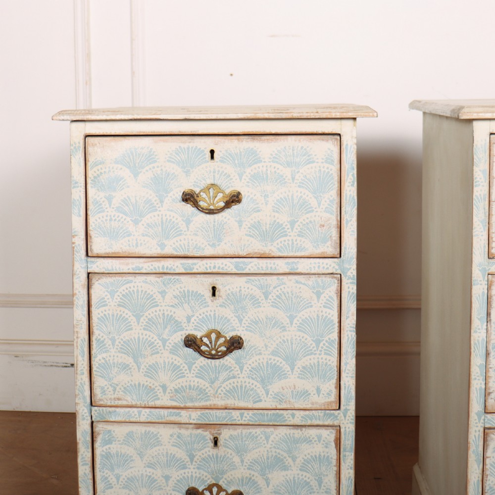 A pair of narrow three-drawer wooden chests featuring off-white distressed paint finish, brass handles, and blue hand-painted fan pattern drawer fronts. View II