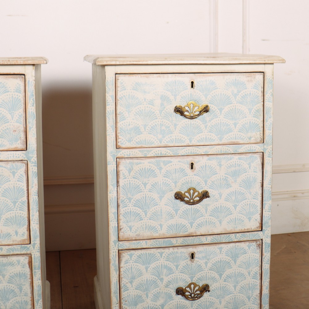 A pair of narrow three-drawer wooden chests featuring off-white distressed paint finish, brass handles, and blue hand-painted fan pattern drawer fronts. View III