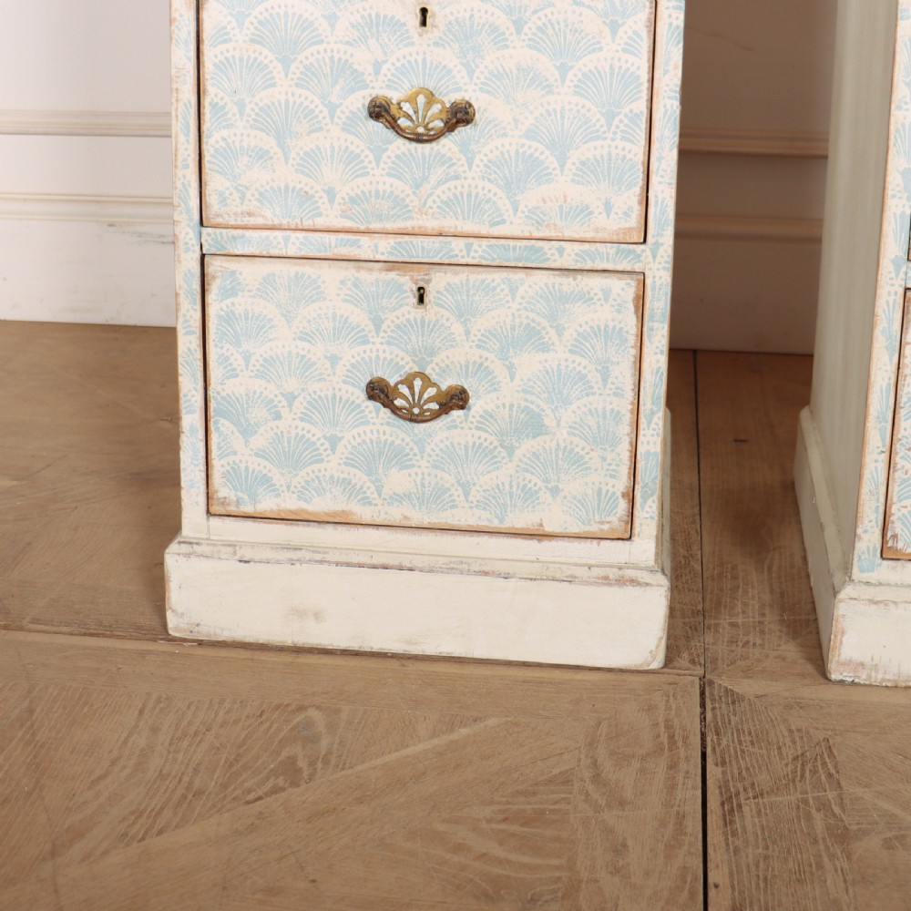 A pair of narrow three-drawer wooden chests featuring off-white distressed paint finish, brass handles, and blue hand-painted fan pattern drawer fronts. View IV
