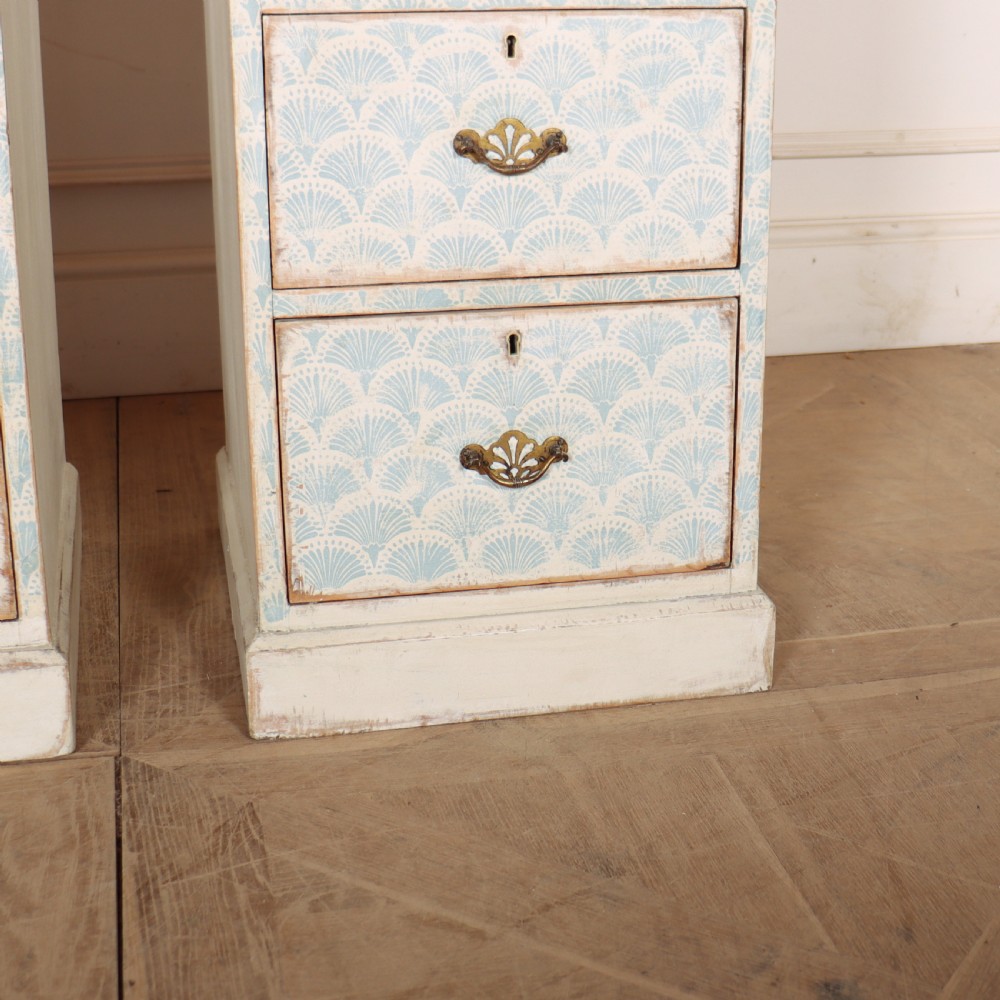 A pair of narrow three-drawer wooden chests featuring off-white distressed paint finish, brass handles, and blue hand-painted fan pattern drawer fronts. View V