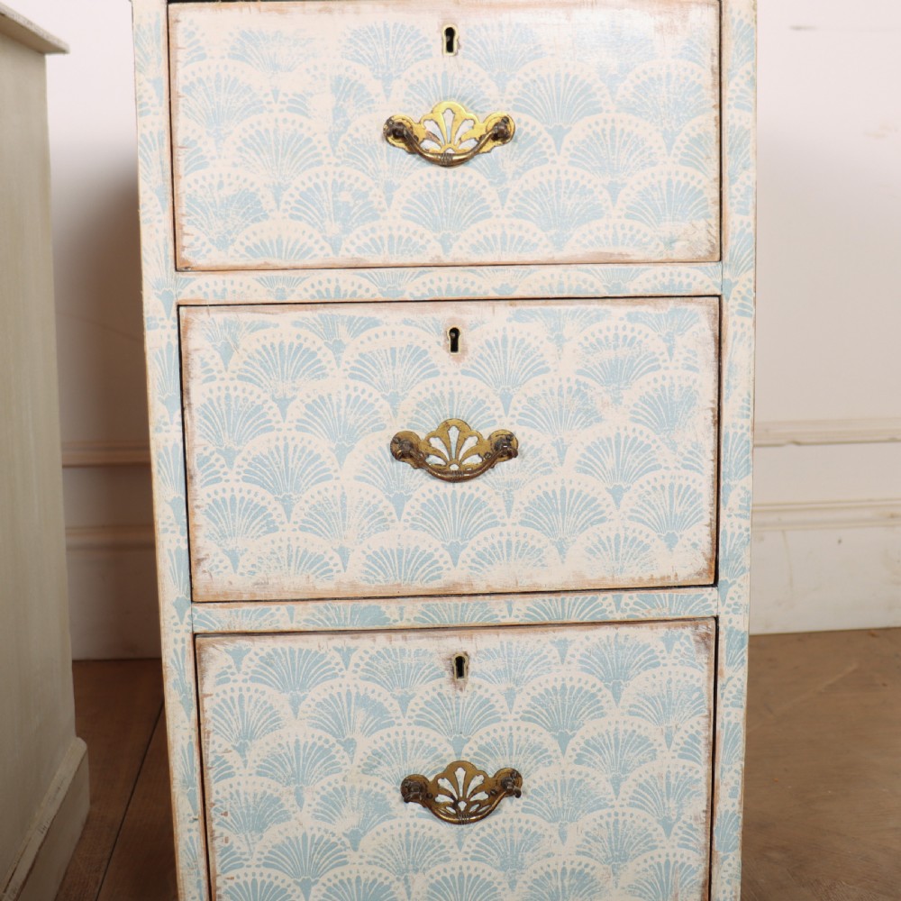A pair of narrow three-drawer wooden chests featuring off-white distressed paint finish, brass handles, and blue hand-painted fan pattern drawer fronts. View VII