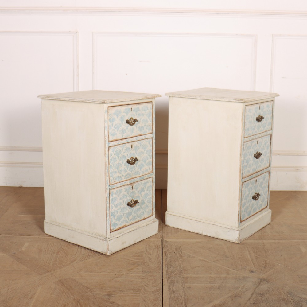 A pair of narrow three-drawer wooden chests featuring off-white distressed paint finish, brass handles, and blue hand-painted fan pattern drawer fronts. View VIII