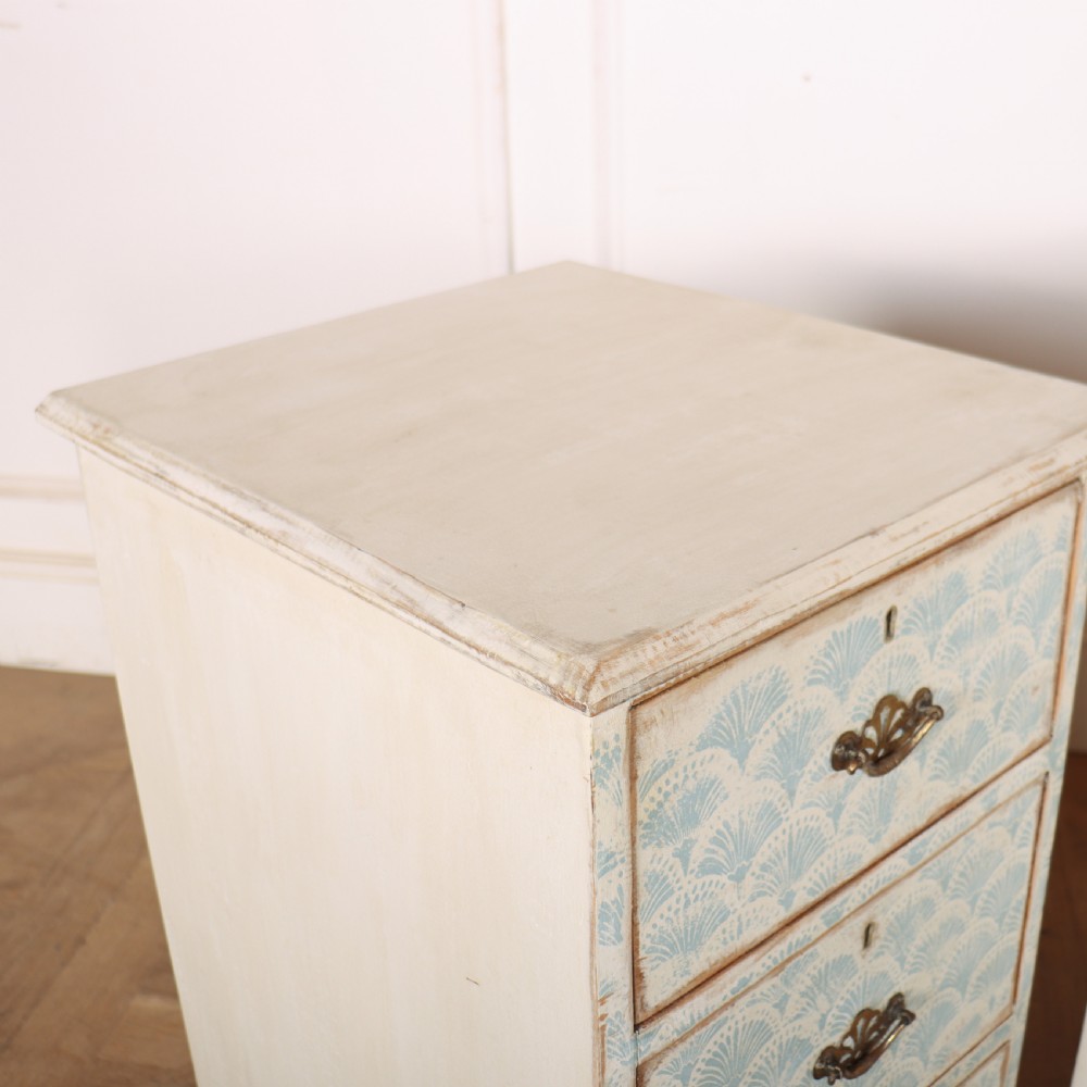 A pair of narrow three-drawer wooden chests featuring off-white distressed paint finish, brass handles, and blue hand-painted fan pattern drawer fronts. View IX