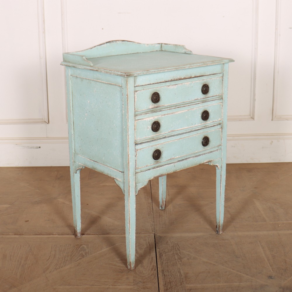 A pale blue painted three-drawer antique bedside cabinet featuring dark round knobs and a low gallery top. View VI