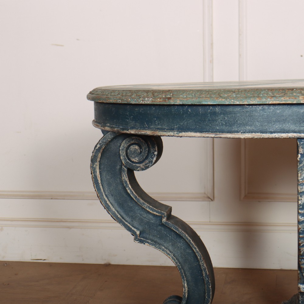 A round blue painted lamp table featuring a starburst pattern top, carved scroll legs, and an X-frame base. View V