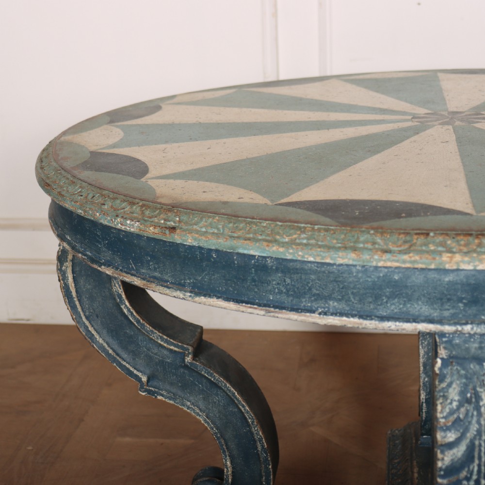 A round blue painted lamp table featuring a starburst pattern top, carved scroll legs, and an X-frame base. View VII