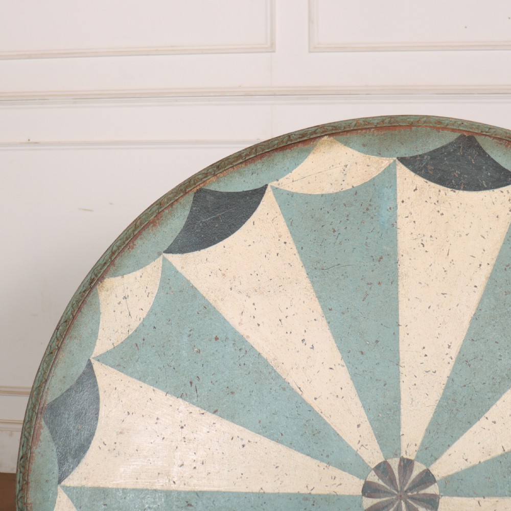 A round blue painted lamp table featuring a starburst pattern top, carved scroll legs, and an X-frame base. View X
